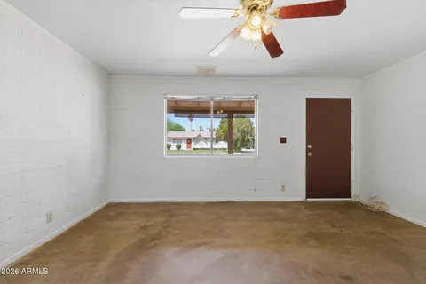 an empty room with windows and fan