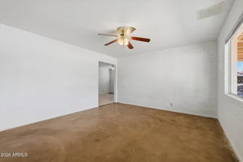 an empty room with windows and fan