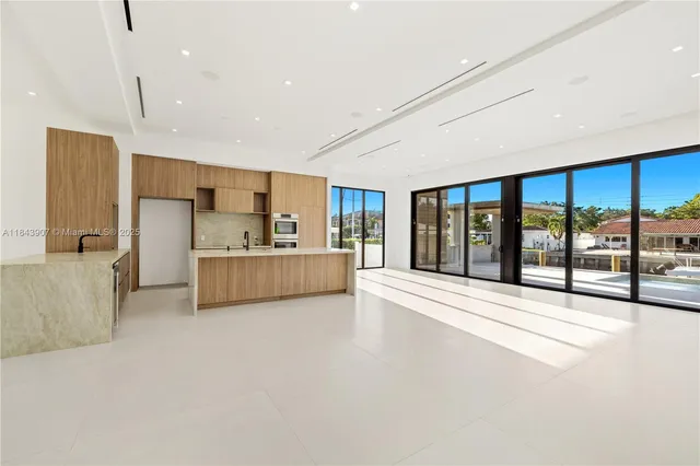 a large kitchen with stainless steel appliances kitchen island a large counter top a refrigerator and a sink