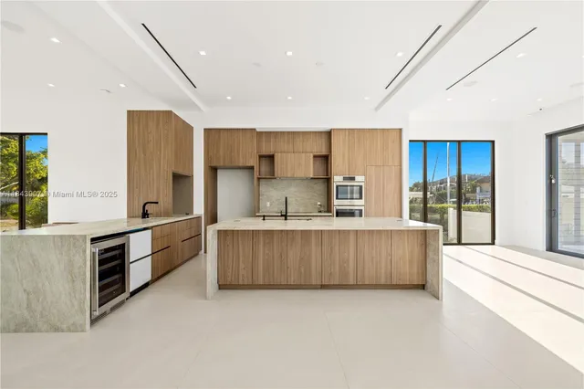 a large kitchen with stainless steel appliances a large counter top a stove and a refrigerator