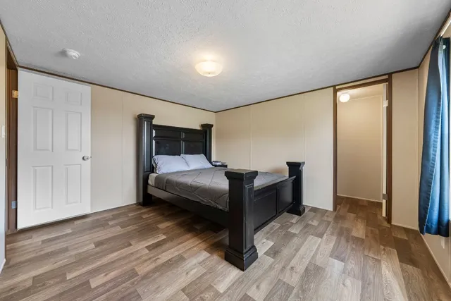 a bedroom with a bed and a dresser with wooden floor