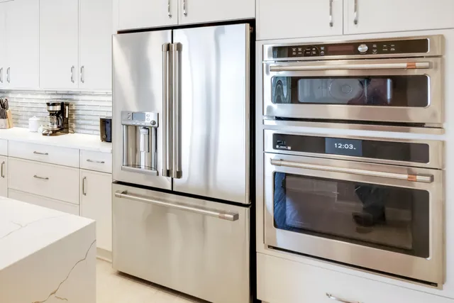 a kitchen with white cabinets and stainless steel appliances