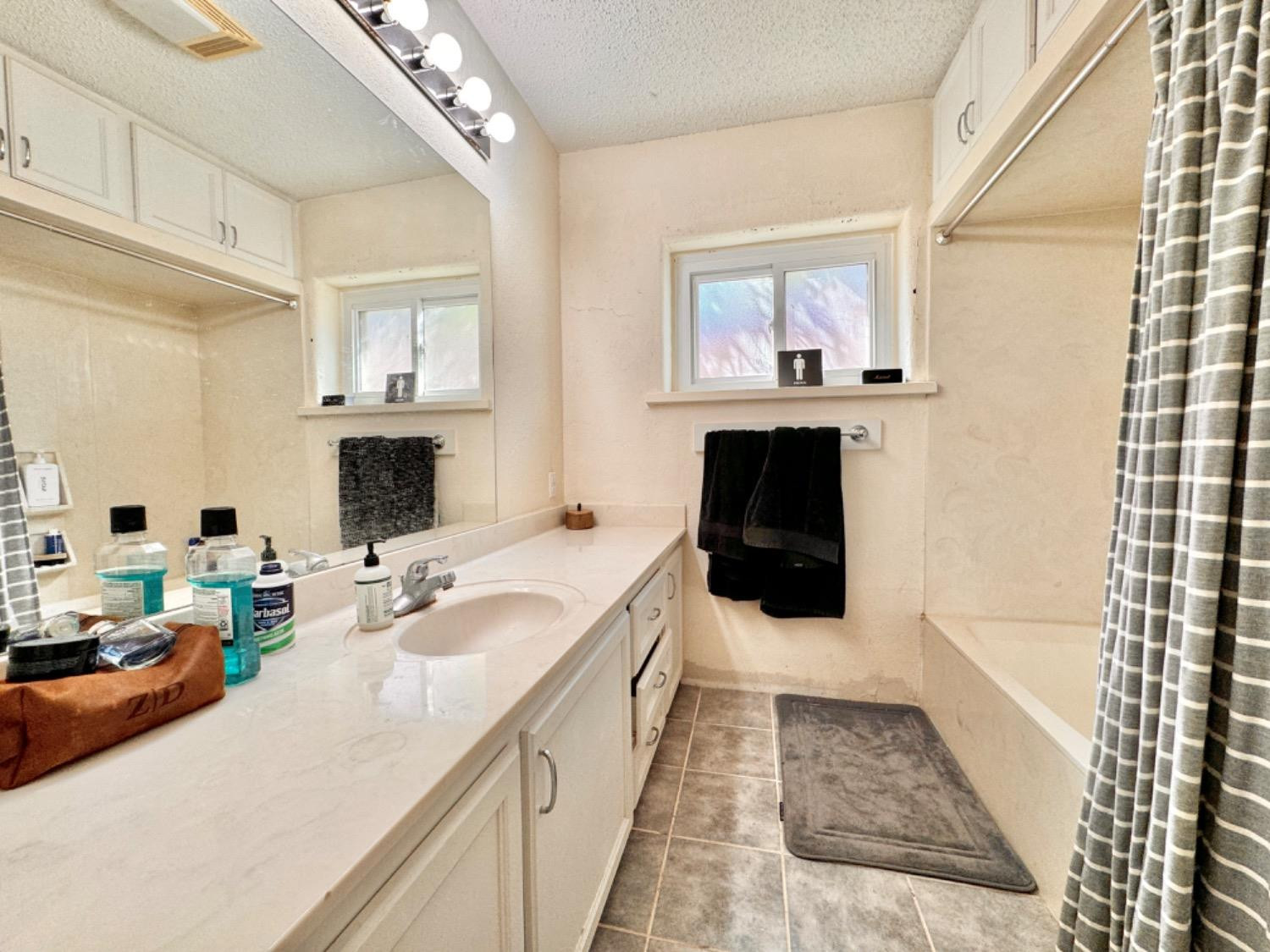 2621 23rd Street Lubbock, TX 79410 - Photo 17 of 38 a bathroom with a tub sink double vanity and mirror