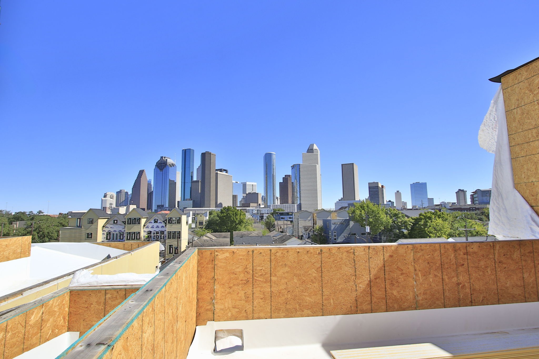 1316 Robin Street, Unit C Houston, TX 77019 - Photo 15 of 45 This photo showcases a rooftop view from a property under construction, featuring a stunning skyline of a city with modern high-rise buildings under a clear blue sky.