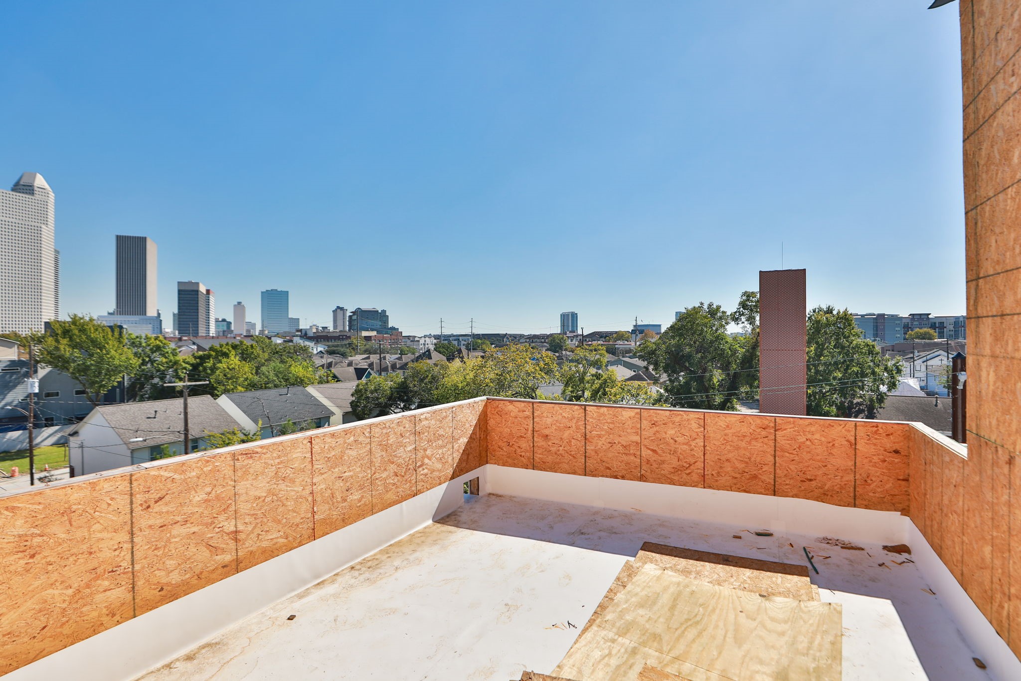1316 Robin Street, Unit C Houston, TX 77019 - Photo 21 of 45 This photo showcases a rooftop under construction with a view of the city skyline in the background. The area offers potential for outdoor living space, with a clear sky and surrounding greenery adding to the appeal.