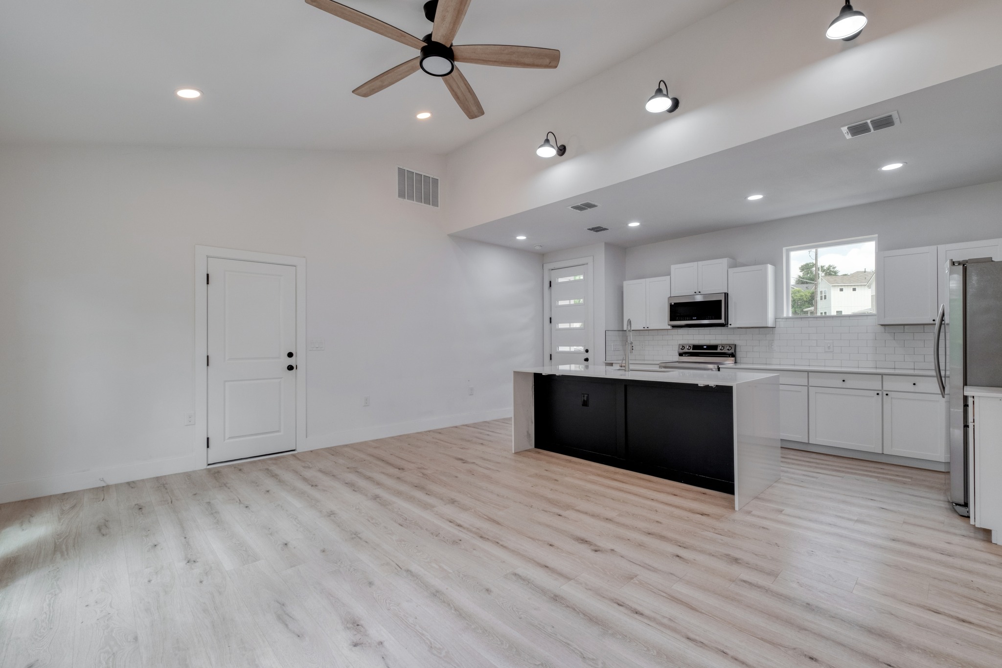 5211 Rob-Scott Street Austin, TX 78721 - Photo 4 of 24 A contemporary open-concept space features light wood flooring, an airy ceiling with a ceiling fan, and a sleek kitchen island.