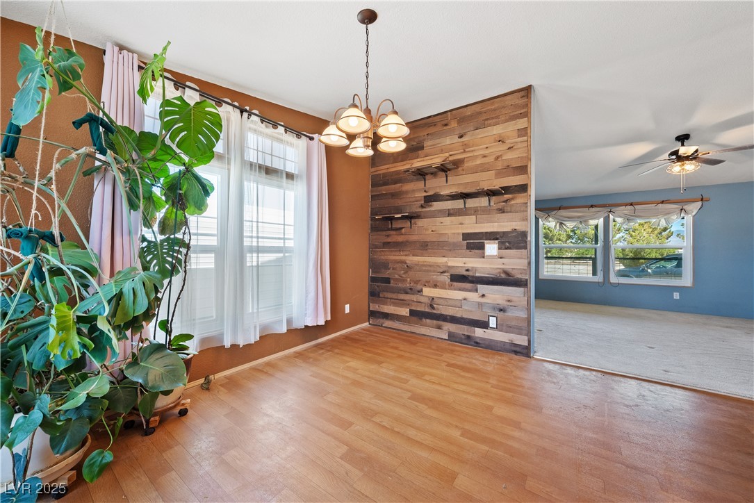 1391 East Casey Road Pahrump, NV 89048 - Photo 12 of 40 Spare room with plenty of natural light, a chandelier, wood finished floors, a ceiling fan, and wood walls