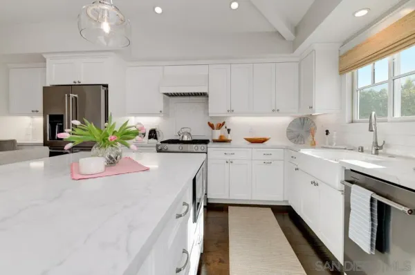 a kitchen with stainless steel appliances a sink a stove and white cabinets