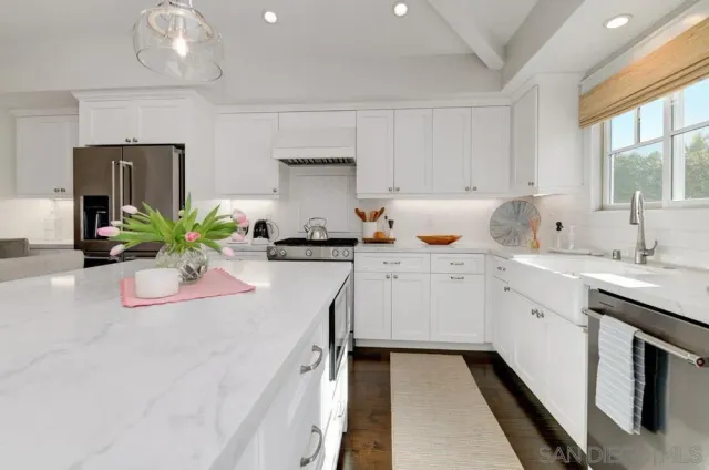 a kitchen with stainless steel appliances a sink a stove and white cabinets