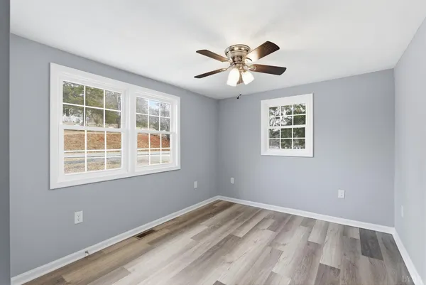 a view of an empty room with a window and wooden floor