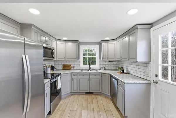 a kitchen with a sink a refrigerator a window and cabinets