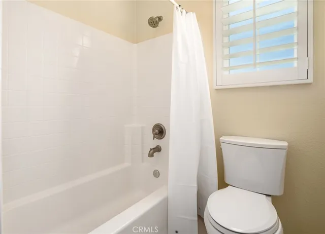 a white toilet sitting next to a bath tub