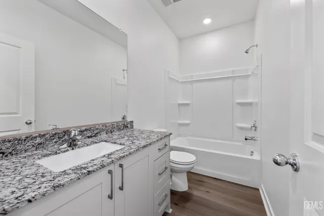 a bathroom with a granite countertop sink a toilet and bathtub
