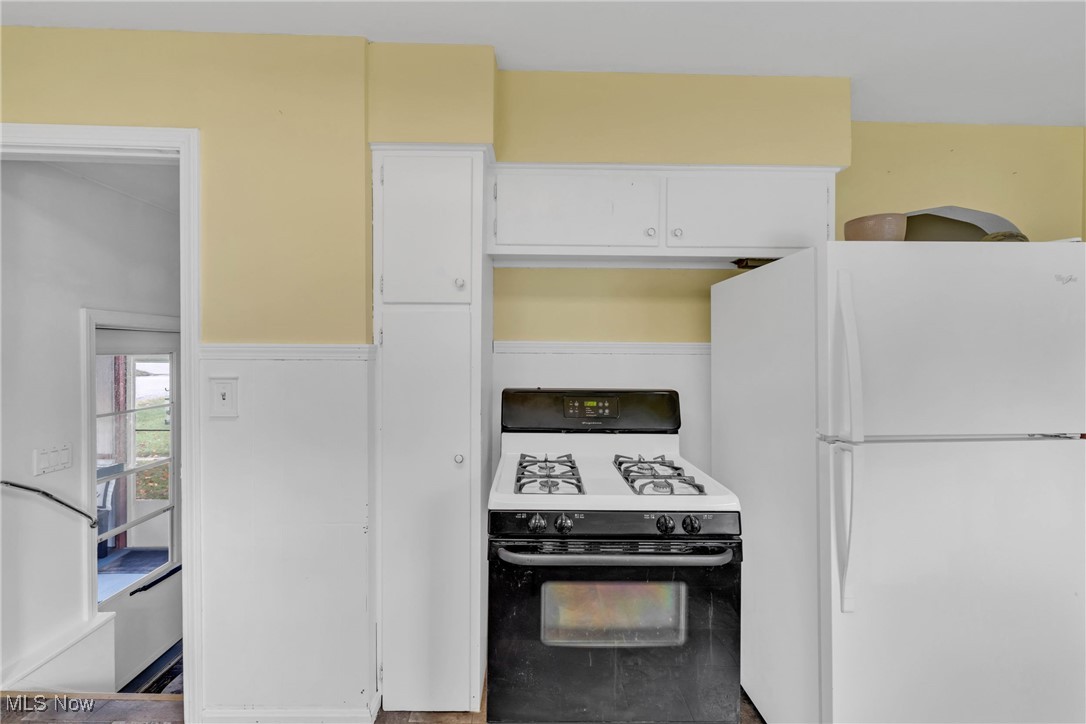 390 Hilliard Road Elyria, OH 44035 - Photo 13 of 30 Kitchen with black gas range, freestanding refrigerator, and white cabinetry