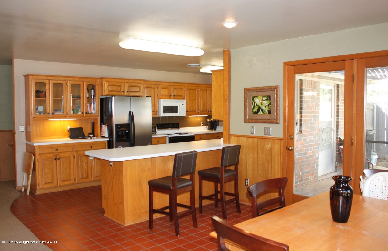 6104 Jameson Road Amarillo, TX 79106 - Photo 10 of 36 a kitchen with a table chairs refrigerator and microwave