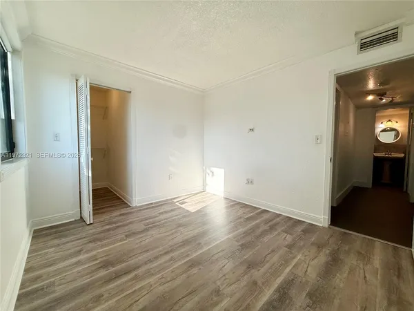 a view of an empty room with wooden floor and closet