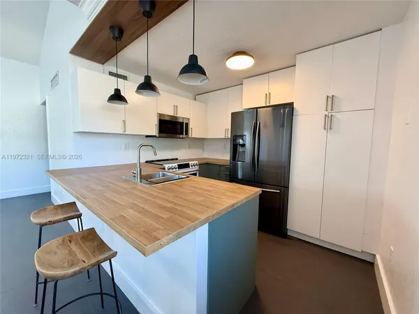 a kitchen with stainless steel appliances granite countertop a refrigerator a stove and a sink with wooden floor