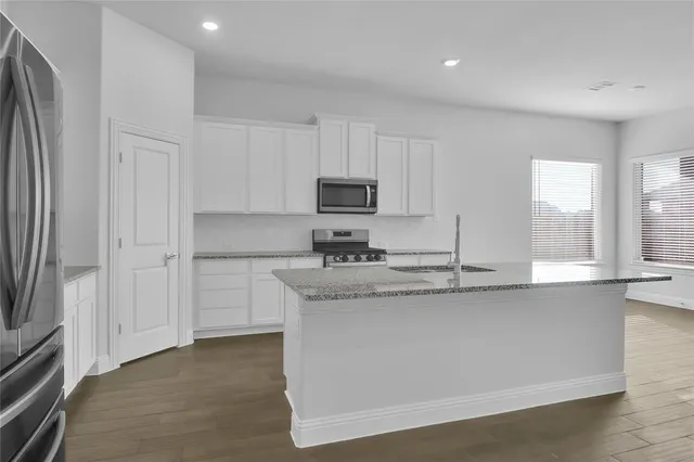 a kitchen with stainless steel appliances granite countertop a stove a sink and a refrigerator