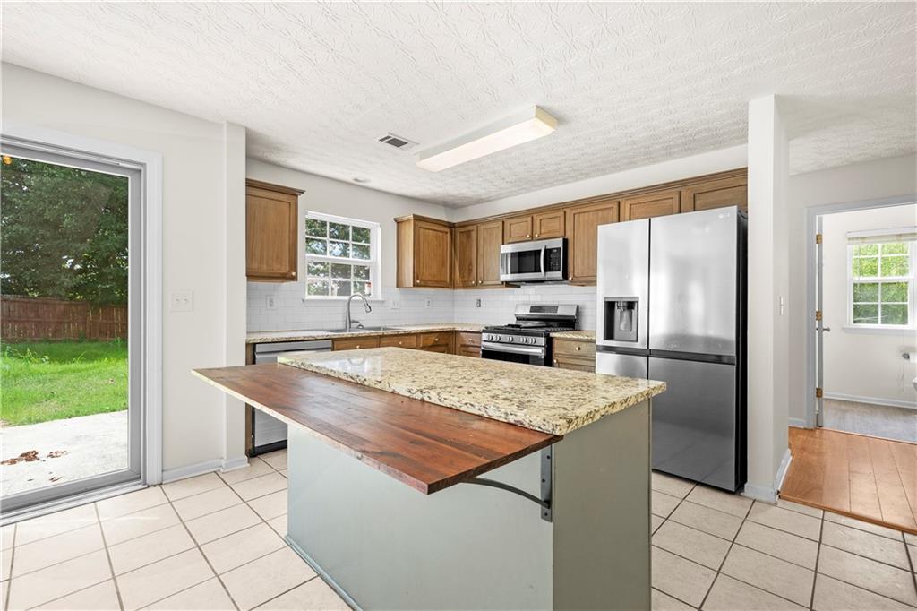 3740 Crescent Walk Lane Northeast Suwanee, GA 30024 - Photo 11 of 39 a kitchen with stainless steel appliances granite countertop a refrigerator a stove and a sink with granite countertops
