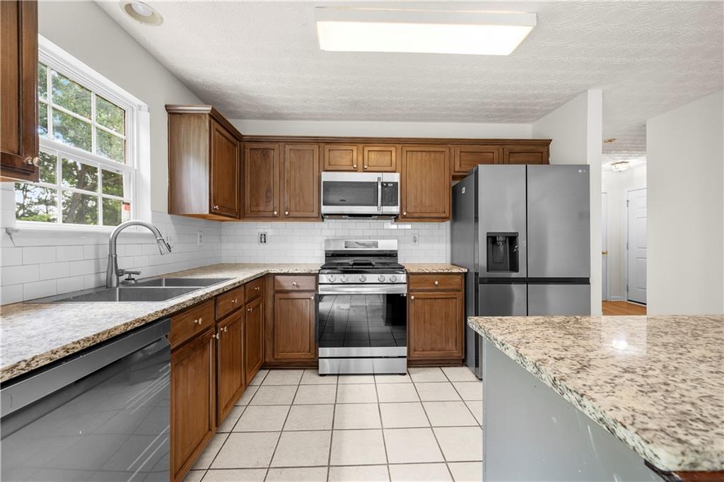 3740 Crescent Walk Lane Northeast Suwanee, GA 30024 - Photo 12 of 39 a kitchen with kitchen island granite countertop a stove sink and refrigerator