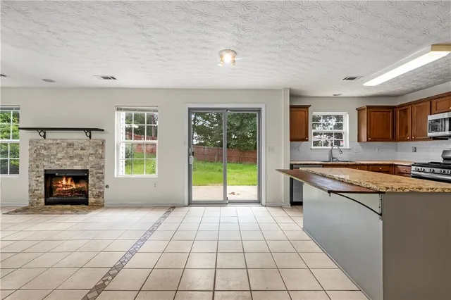 a open kitchen with granite countertop a stove top oven a sink dishwasher and a fireplace with wooden floor