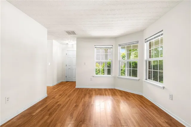 an empty room with wooden floor and windows