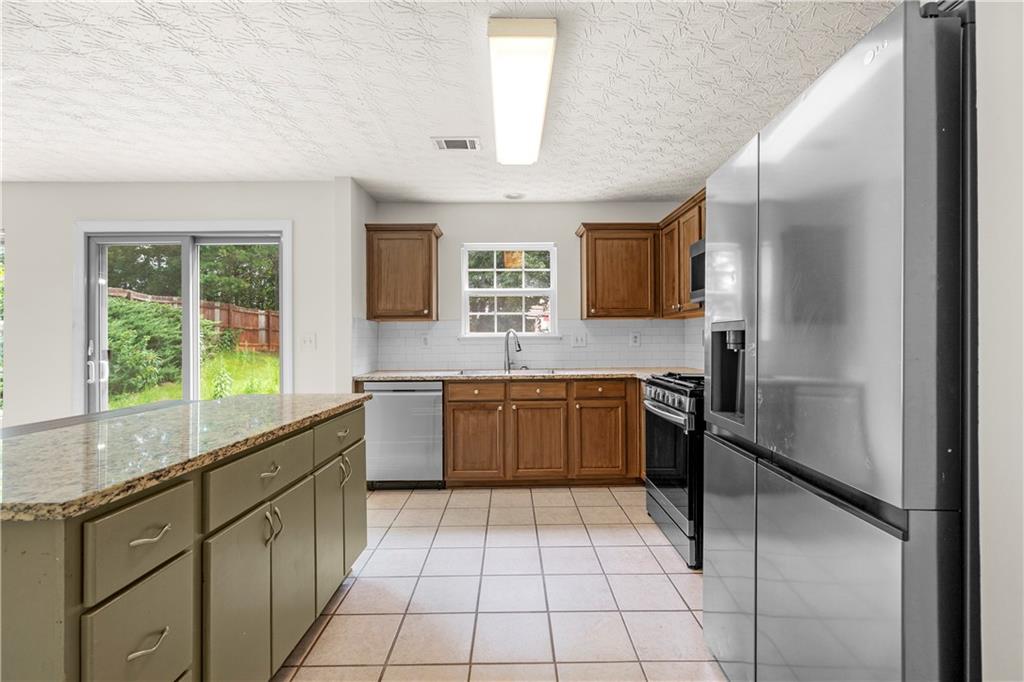 3740 Crescent Walk Lane Northeast Suwanee, GA 30024 - Photo 10 of 39 a kitchen with stainless steel appliances granite countertop a refrigerator and a sink