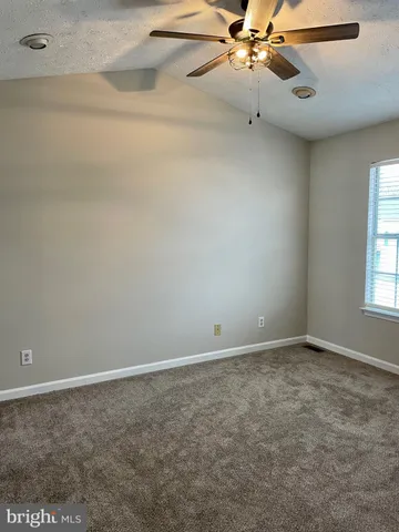 an empty room with a ceiling fan and window