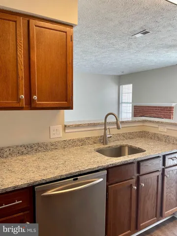 a view with granite countertop a sink and cabinets