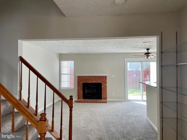 a view of an empty room with fireplace and stairs