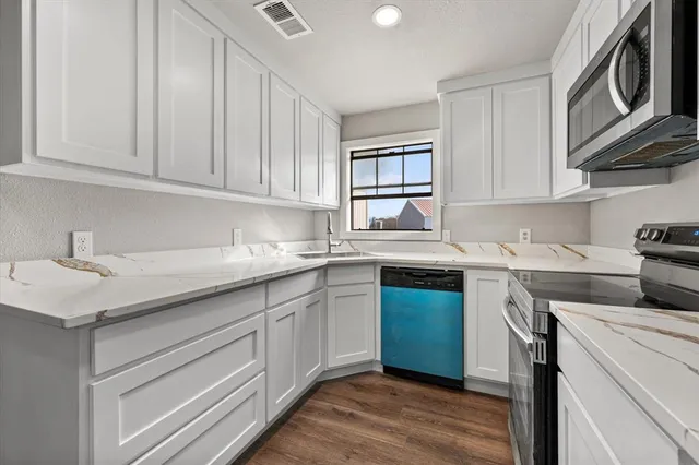 a kitchen with granite countertop a sink stainless steel appliances and cabinets
