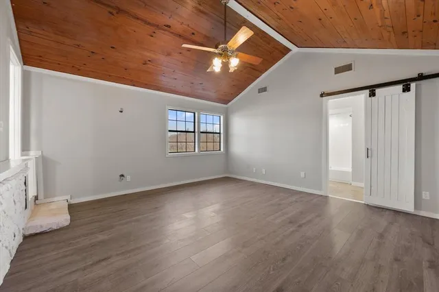 an empty room with wooden floor chandelier fan and windows