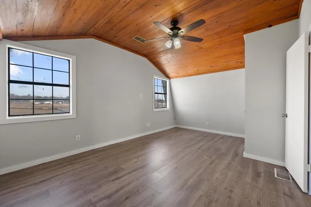 an empty room with wooden floor chandelier fan and windows