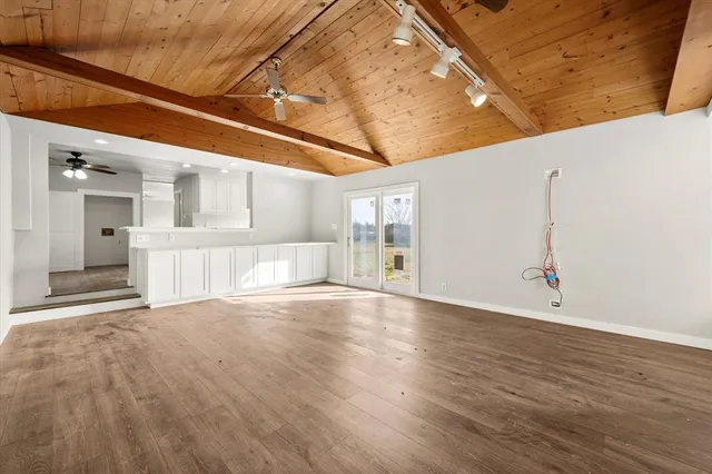 a view of an empty room with wooden floor and a ceiling fan