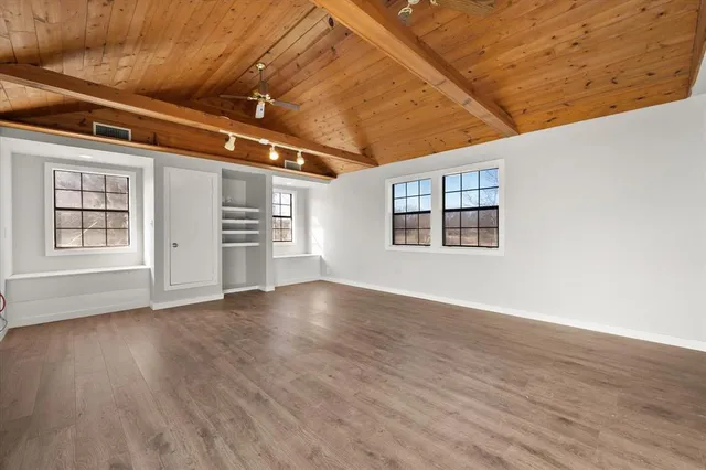a view of an empty room with window and wooden floor