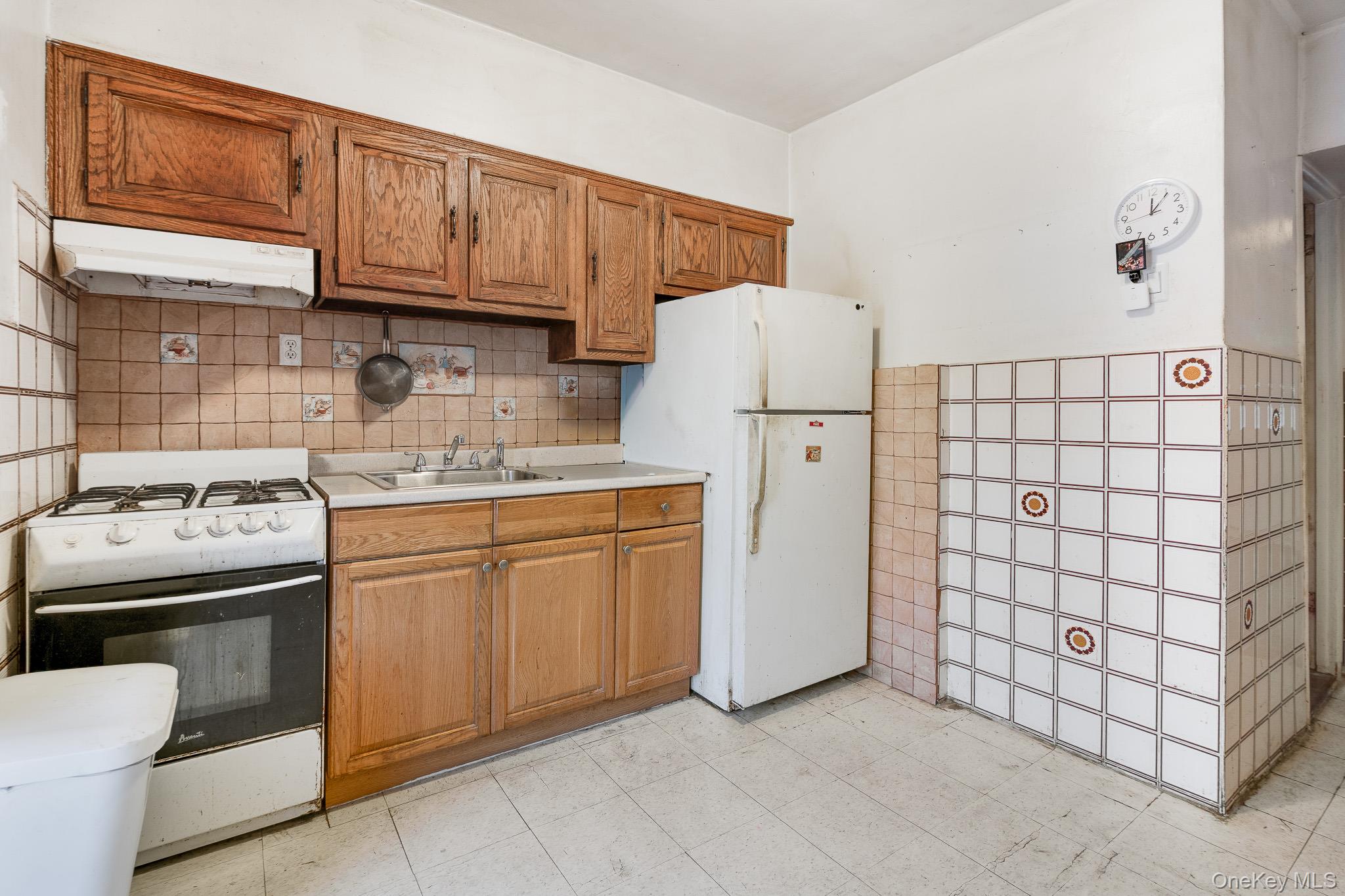 2437 Buck Street Bronx, NY 10461 - Photo 30 of 38 a kitchen with a sink a stove a refrigerator and cabinets