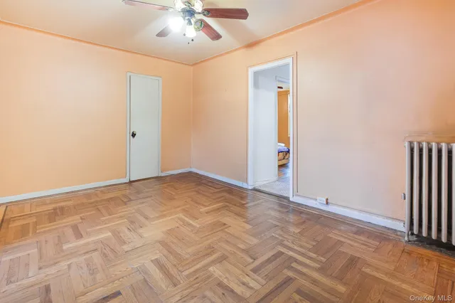 an empty room with chandelier fan and windows