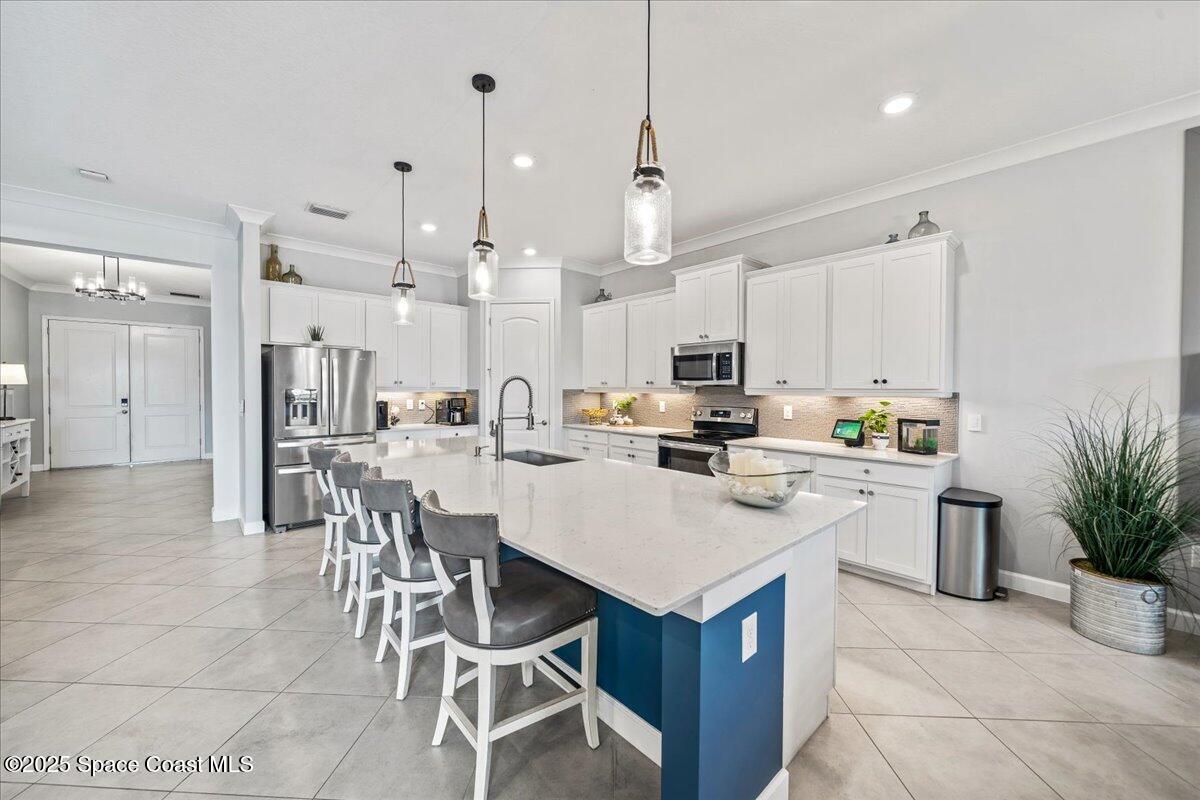 2190 Caravan Place Melbourne, FL 32940 - Photo 17 of 46 a kitchen with stainless steel appliances kitchen island a table and chairs in it