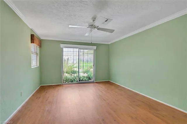 an empty room with wooden floor fan and windows