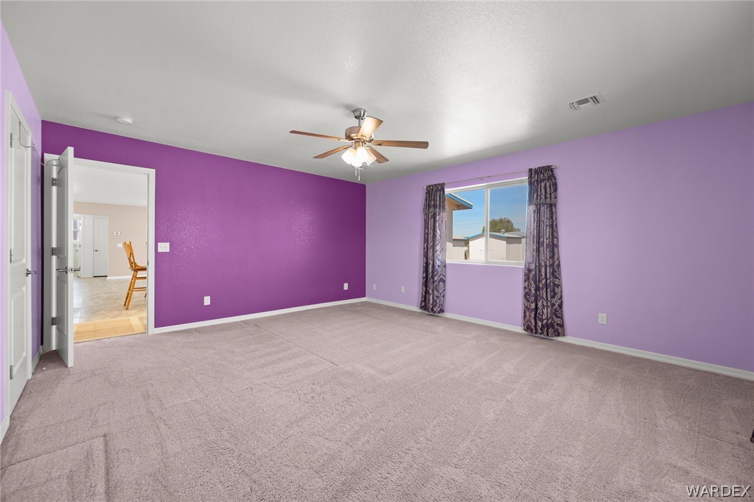 3411 West Carmichael Road Golden Valley, AZ 86413 - Photo 24 of 97 Unfurnished bedroom featuring light colored carpet and a ceiling fan