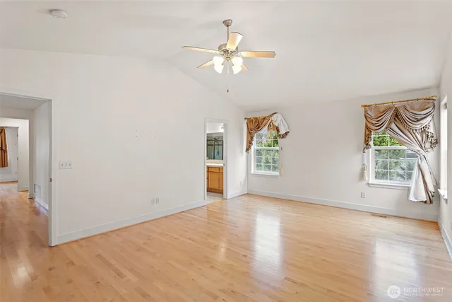 an empty room with wooden floor chandelier fan and windows