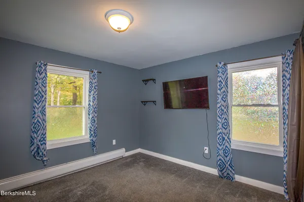 a view of an empty room with a window and a dresser