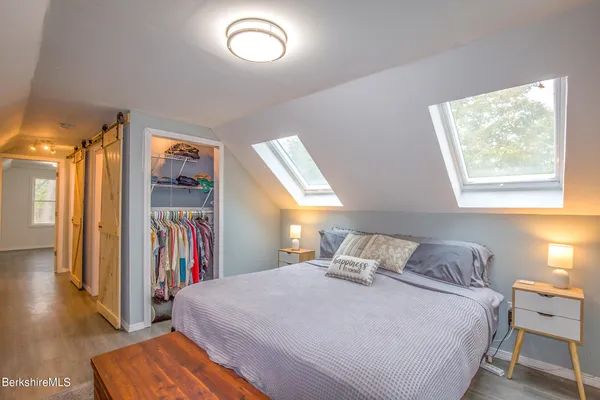 a bedroom with a bed and a large mirror next to a window