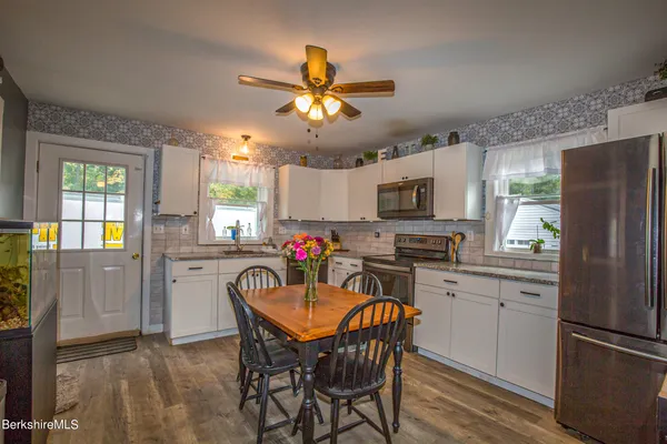 a kitchen with stainless steel appliances granite countertop a dining table chairs refrigerator and microwave