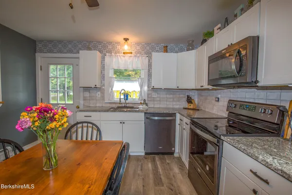 a kitchen with stainless steel appliances granite countertop a stove a sink and a microwave