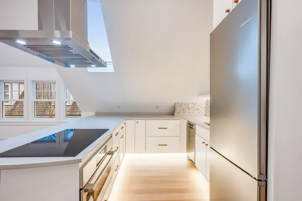 a kitchen with stainless steel appliances granite countertop a sink a stove and white cabinets