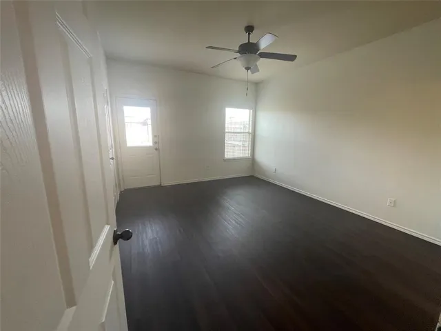 an empty room with wooden floor and windows with curtains