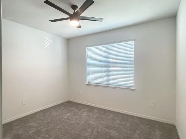 an empty room with a window and a fan
