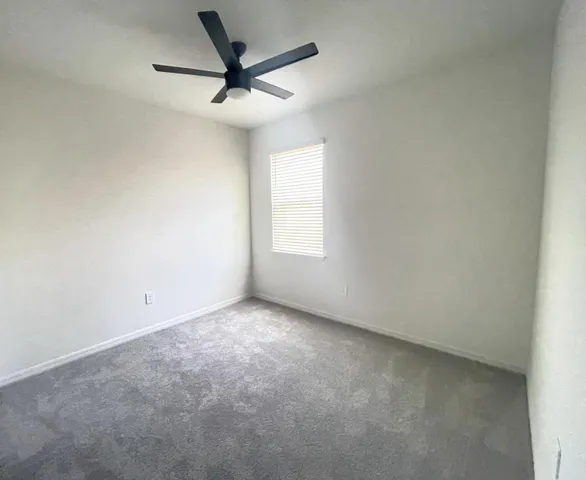 an empty room with a window and a fan