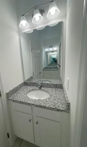 a bathroom with a granite countertop sink and a mirror